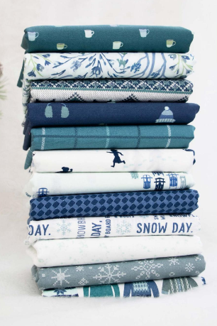 Collection of 12 playing in the snow winter themed fat quarter fabrics for quilting, including dark blue, gray, teal and white designs. 